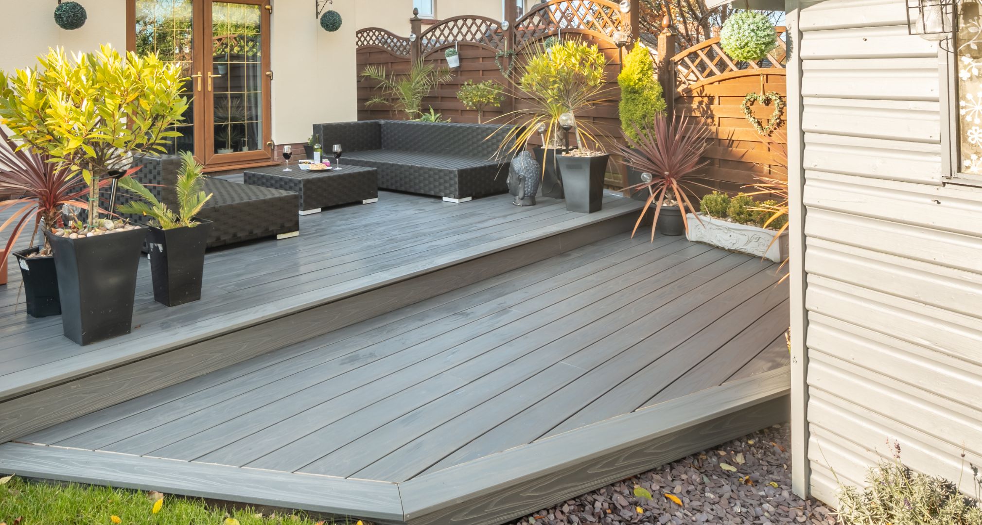 Alchemy composite decking accompanied with garden furniture and potted plants