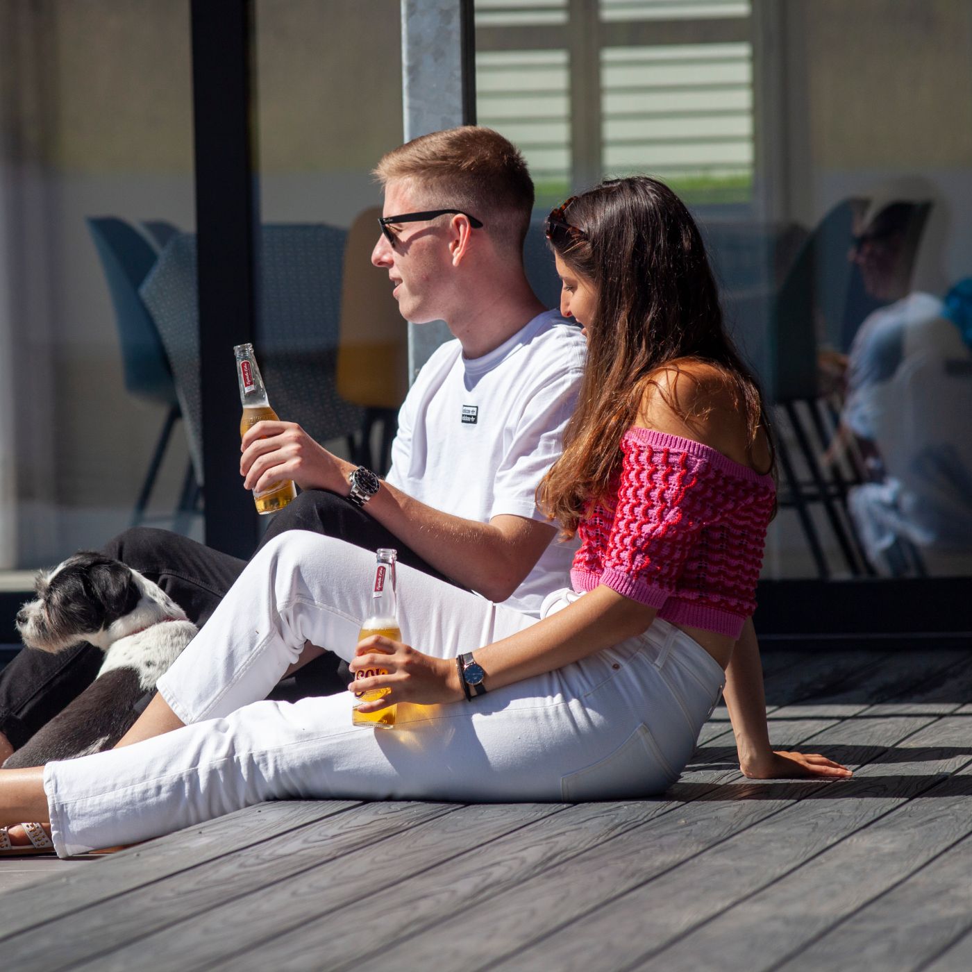 Young couple enjoying a drink whilst sitting on their Alchemy decking