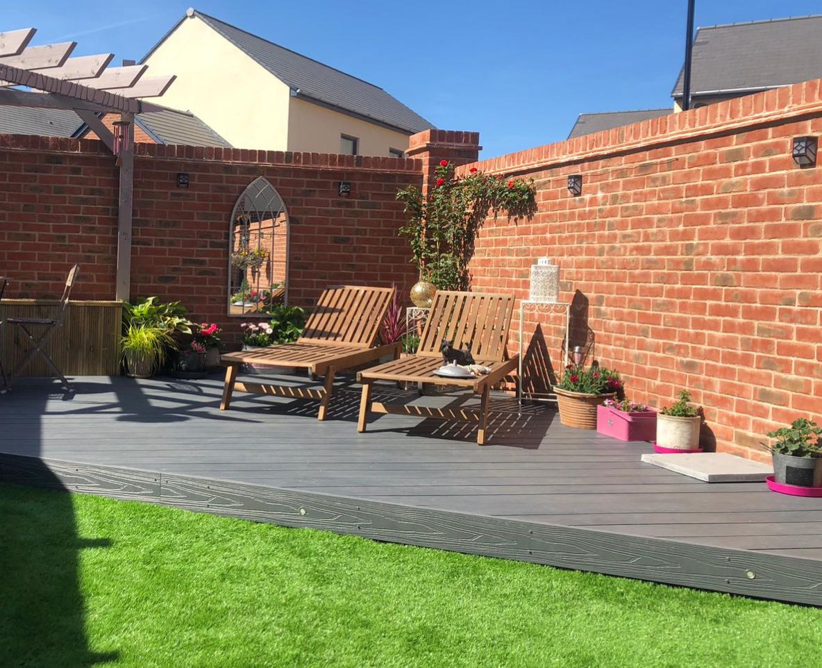 Alchemy Urban decking in a back garden with two sun loungers and plants on top